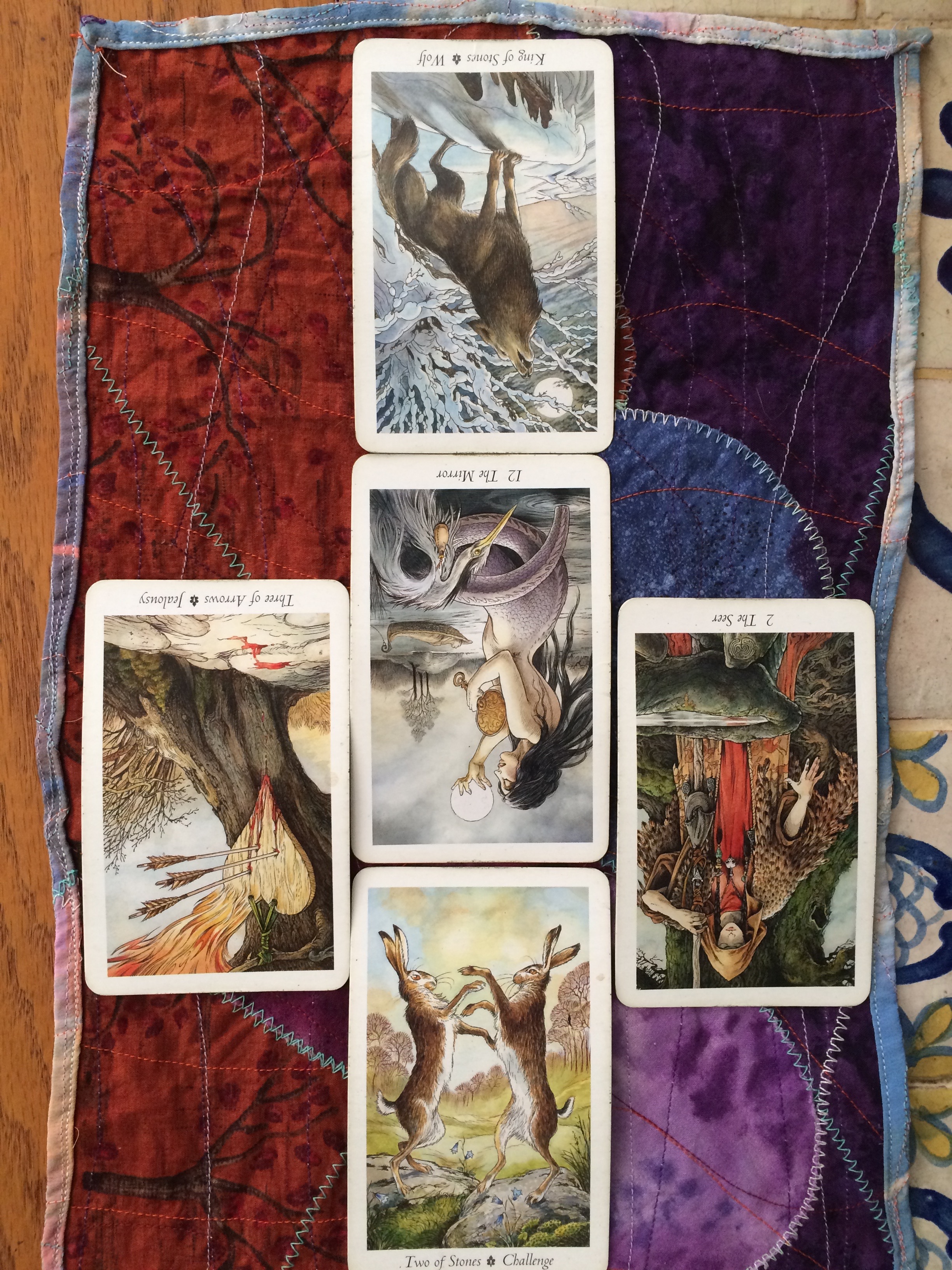 close up of five tarot cards laid out on a purple and red cloth