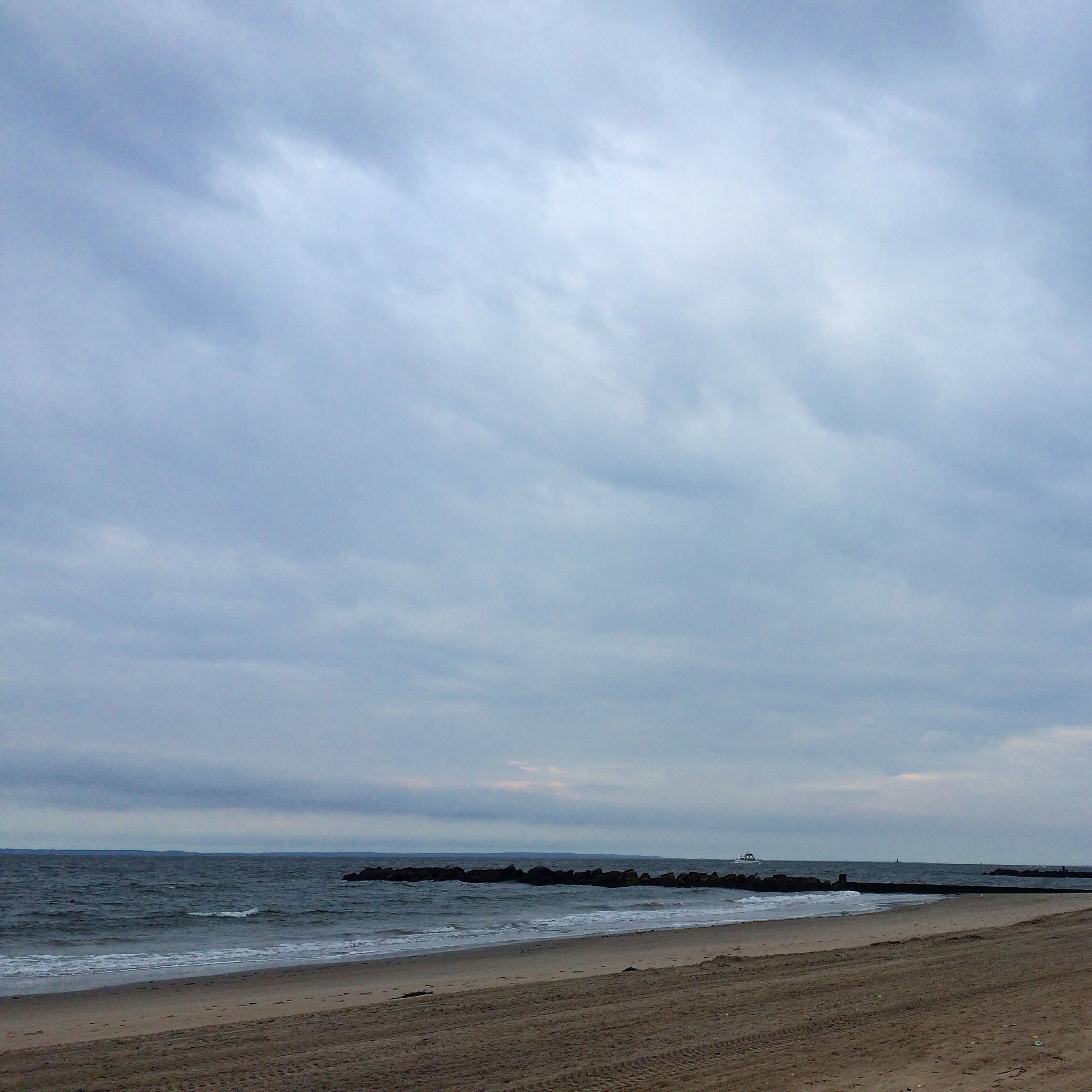 a cloudy morning sky swoops over a small stretch of Brighton Beach